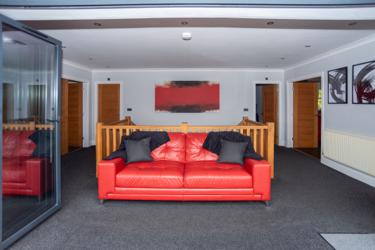 Bright, immaculate open-plan upstairs space with a comfy sofa facing the bi-fold doors, opening out to the balcony and its beautiful sea views.