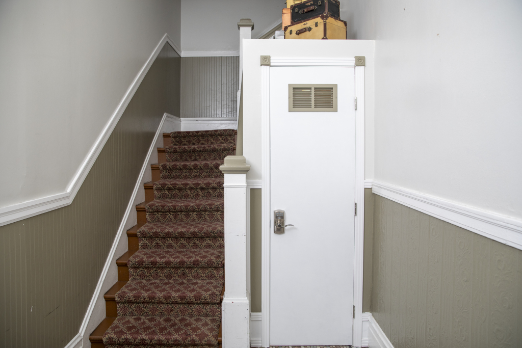 A staircase with a red carpet leading up to a white door.