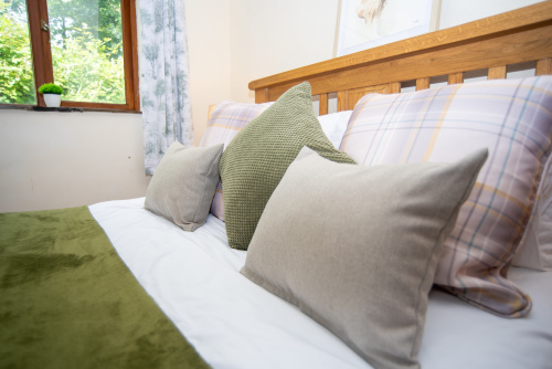 Designed for restful nights, the beautifully dressed bedroom combines natural tones, cosy furnishings and tranquil garden views.