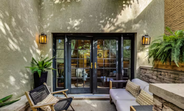 Step onto the serene patio, featuring cozy seating, lush greenery, and charming lantern-style lighting. Framed by elegant French doors, this outdoor space is perfect for morning coffee or evening relaxation amidst a tranquil and inviting atmosphere.