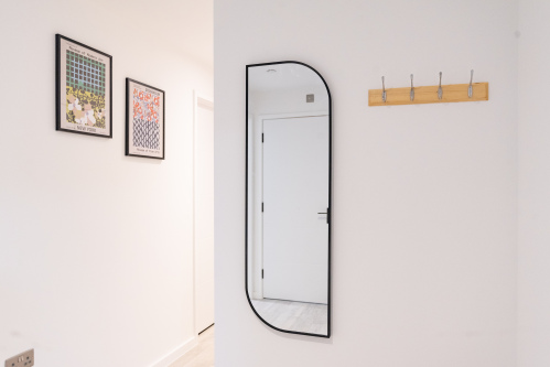 Welcoming entryway with coat hooks and full-length mirror.