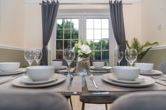 A bright, open and clean dining room with a table seating six, fully equipped with everything needed for home-from-home dining — perfect for family meals or unwinding after long workdays.