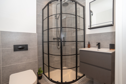 A modern second bathroom with a shower enclosure and rain shower head, complete with complimentary shower gel, shampoo and conditioner, plus all towels provided for a premium home-from-home stay in Birmingham.