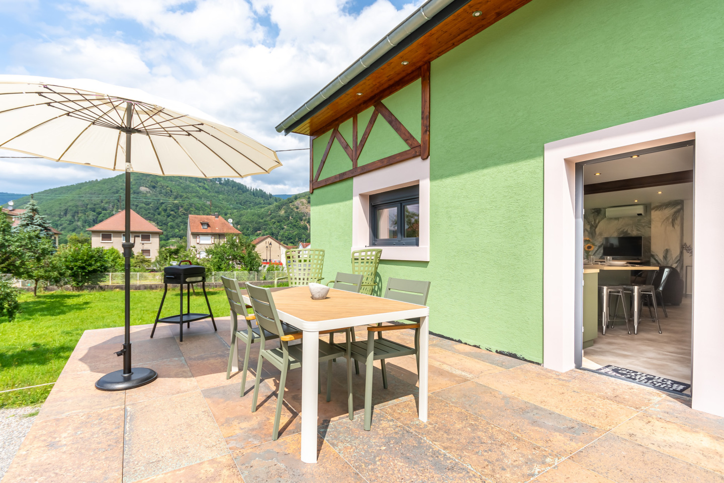 La terrasse avec son coin repas, son parasol et ses fauteuils relaxants