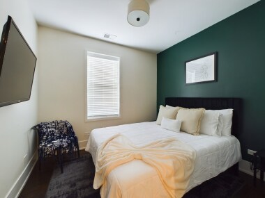 Unwind in this cozy queen bedroom 2, featuring a plush bed and a soothing green accent wall. Simple yet elegant decor creates a serene atmosphere, making it the perfect space to relax and recharge.
