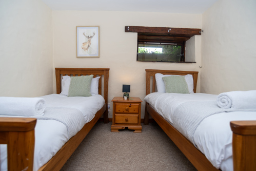 Twin Bedroom with Original Mill Character - Two singles with fresh hotel-quality linens, towels on arrival and the original mill window beam as a charming feature