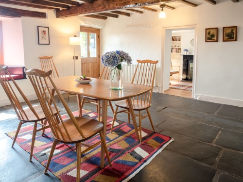 Characterful dining room with exposed beams and original slate floor, completed with a wood burner stove