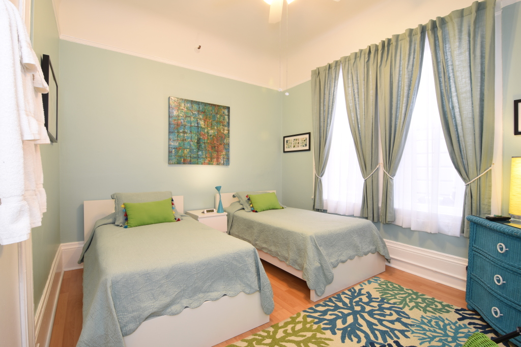 A hotel room with two twin beds, a window with curtains, and a dresser.