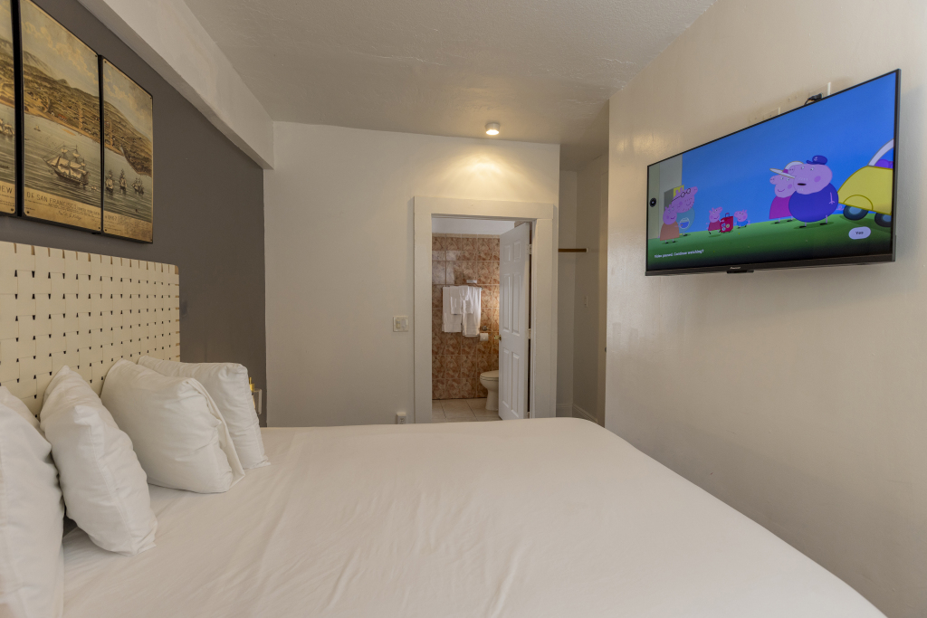 A hotel room with a large bed, flat-screen TV, and doorway to bathroom
