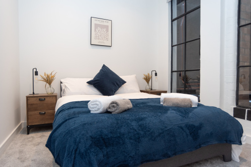 A stylish double bedroom with hotel-quality crisp linens and fresh towels provided. Bedroom one of three in this two-floor apartment, sleeping up to 8 guests - book your Birmingham stay with Affluxi.