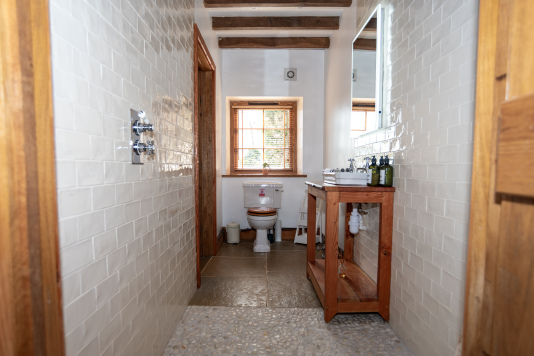 Easy-access downstairs en suite featuring a rainfall shower, toilet and sink — perfect for guests needing accessible facilities