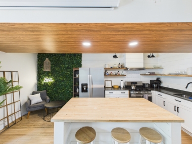 The kitchen’s clean lines meet a splash of greenery, making meal prep feel as inviting as the dining table that awaits.