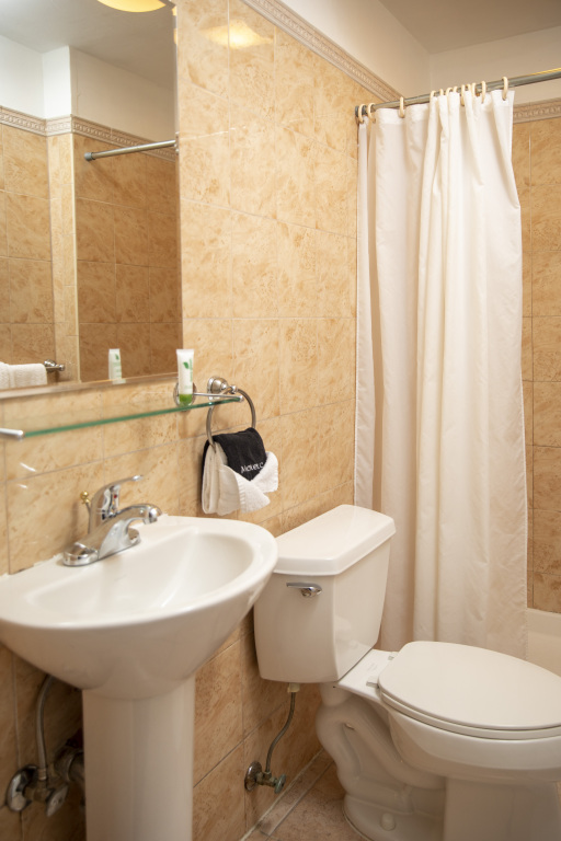 A bathroom with a white toilet, pedestal sink, and tiled walls