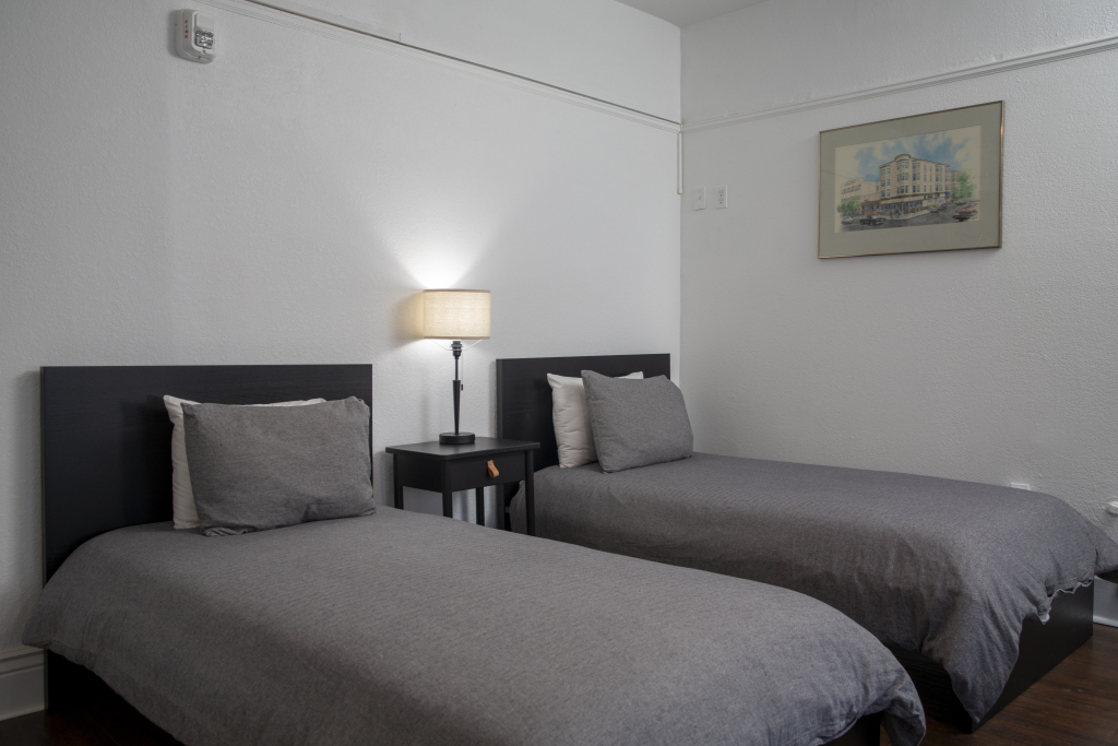 A hotel room with two beds, a nightstand, and a picture on the wall.