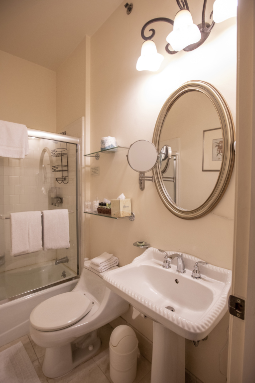 A clean bathroom with a toilet, sink, mirror, and shower