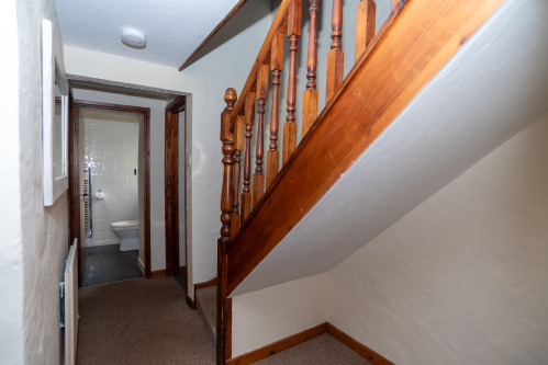 Ground Floor Hallway - The warm pine staircase connects the bedrooms below to the open-plan living level above, with the bathroom directly accessible from the ground floor