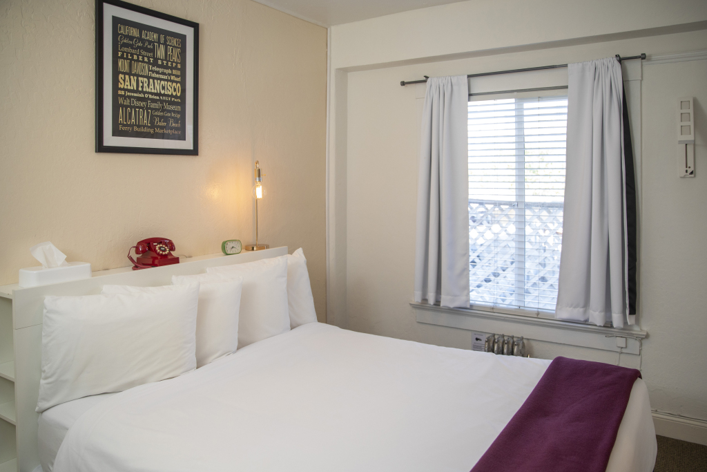 A hotel room with a bed, window, and nightstand.
