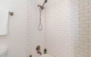 The bathroom features a bathtub and a shower with a detachable, adjustable shower head, combining functionality with comfort for a refreshing start or relaxing end to your day.