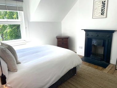 Double bedroom with cast-iron fireplace and leafy garden views