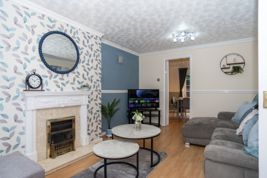 A spacious living room with a full electric reclining sofa, sofa bed, Smart HD TV and a cosy, comfortable setting for relaxing.