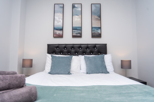 Spacious, welcoming bedroom featuring tasteful artwork and a calm, relaxing atmosphere.