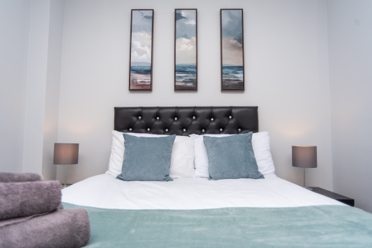 Spacious, welcoming bedroom featuring tasteful artwork and a calm, relaxing atmosphere.