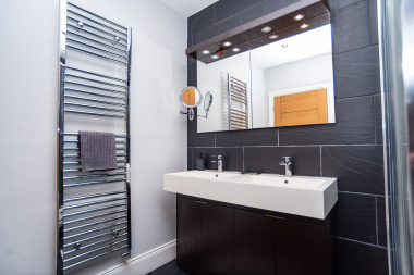 Luxury double-sink ensuite with a sleek modern finish and a heated towel rail for added comfort.