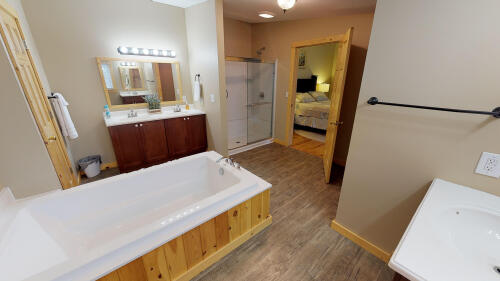 Large bathroom off Bedroom 1 equipped with stand up shower, bath tub, & vanities.