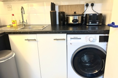 Kitchen with: toaster, Airfryer, kettle, slow cooker, chopping board, mugs, drinking glasses, cutlery, paper towels