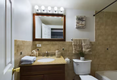 Start your day in this elegant bathroom with a spacious vanity, soft lighting, and polished finishes. The tiled shower-tub combo and plush towels add a touch of comfort for a relaxing experience.