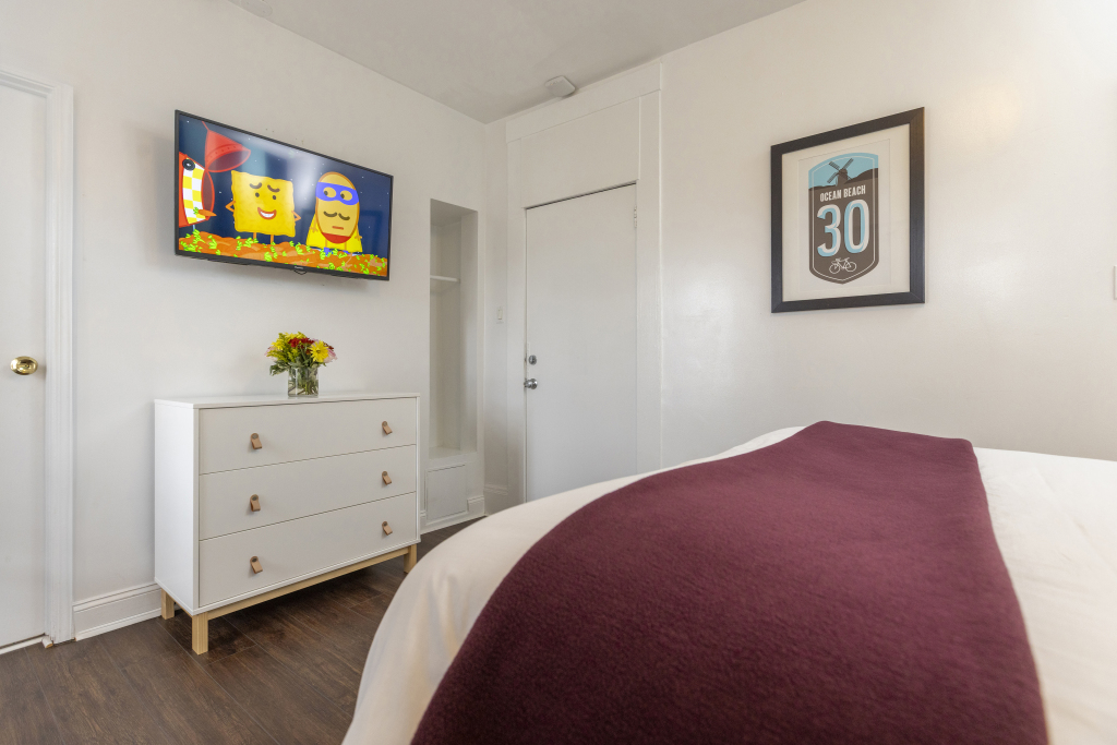 A hotel room with a bed, dresser, and TV