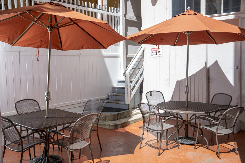 A small outdoor seating area with metal tables and chairs under orange umbrellas