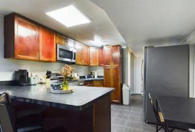 Prepare delicious meals in this spacious kitchen, boasting rich wooden cabinetry, stainless steel appliances, and a sleek countertop with a cozy breakfast bar. The perfect blend of style and functionality for cooking and gathering!