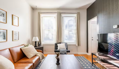 Step into a living room exuding timeless elegance, with a leather couch that transforms into a futon, big windows for natural light or privacy, and a 55” TV. Relax in a sophisticated yet cozy setting, perfect for any mood.