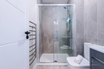 A modern bathroom featuring a shower, a towel rack, and a radiator for added comfort.