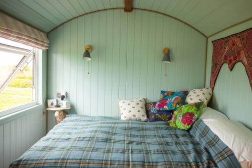 Bed in Mulsford Shepherd Hut with picture widow looking across the countryside 