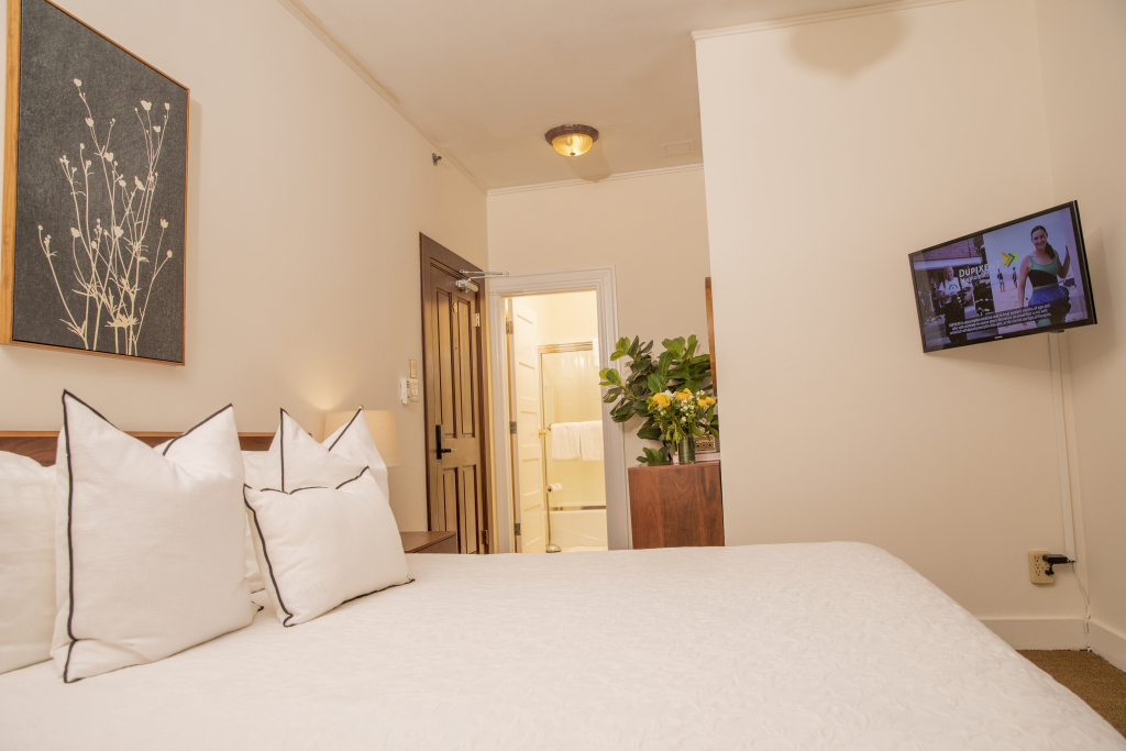 A hotel room with a bed, TV, and doorway to bathroom