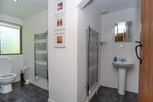 Bathroom area with heated towel rails and sink points either side of a central wall. Master bathroom contains bath with overhead shower, complimentary toiletries, and towels provided for a relaxing stay