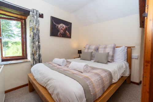 Relax in the inviting master bedroom, featuring a comfortable double bed, countryside charm and views across the cottage grounds.