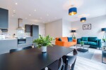 A spacious living room featuring a large TV and cosy sofas, along with a fully equipped kitchen, perfect for relaxing after a day of exploring.