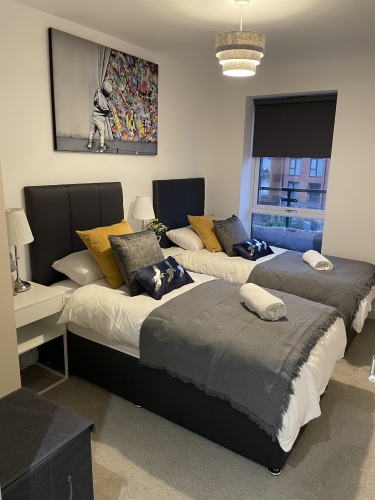 The Harold Wood Luxurious Apartment - 1 Minute From Station - Gated Parking  - Slumber in Style with Urban Views: Unwind in our Guest Room with Cozy Single Beds and Luxe Linens, Gazing at the Cityscape Beyond