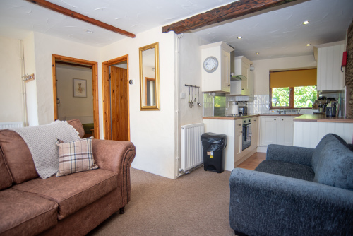 The bright open-plan living space blends traditional cottage character with modern comforts, creating a welcoming setting to relax after a day exploring.