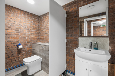 Bathroom in the lower ground floor, clean and tidy with industrial exposed brickwork