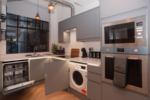 A bright, brand-new modern kitchen with fully integrated appliances including dishwasher, cooker, microwave and washing machine, plus complimentary tea, coffee and sugar - everything needed for a comfortable short or long-term stay.