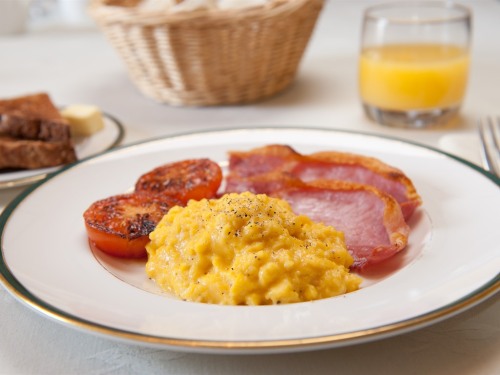 Creamy scrambled eggs, fresh tomatoes and grilled smoked bacon