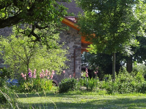 La maison vue du potager. L'été on apprécie l'ombre des arbres et le ruisseau dans les transats à disposition