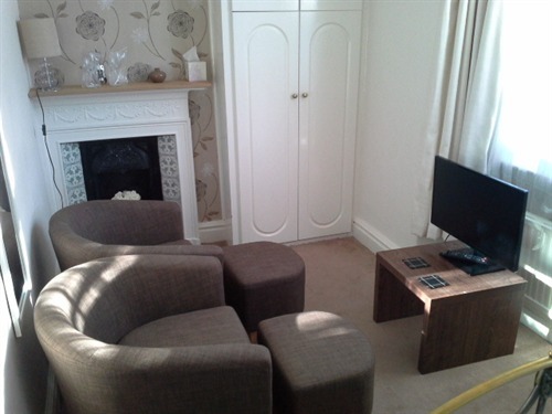 Guest room seating area with Smart TV and original Victorian fireplace.