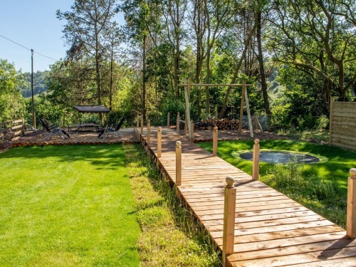 Garden with boardwalk, children's playground including trampoline, swings and zip wire